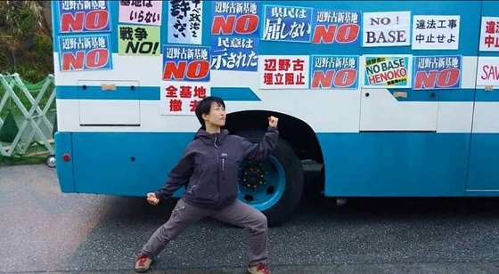 滋賀県から辺野古に押しかけたキム・キガン。警察車両に無断でポスターを貼り、貶めるポーズ。